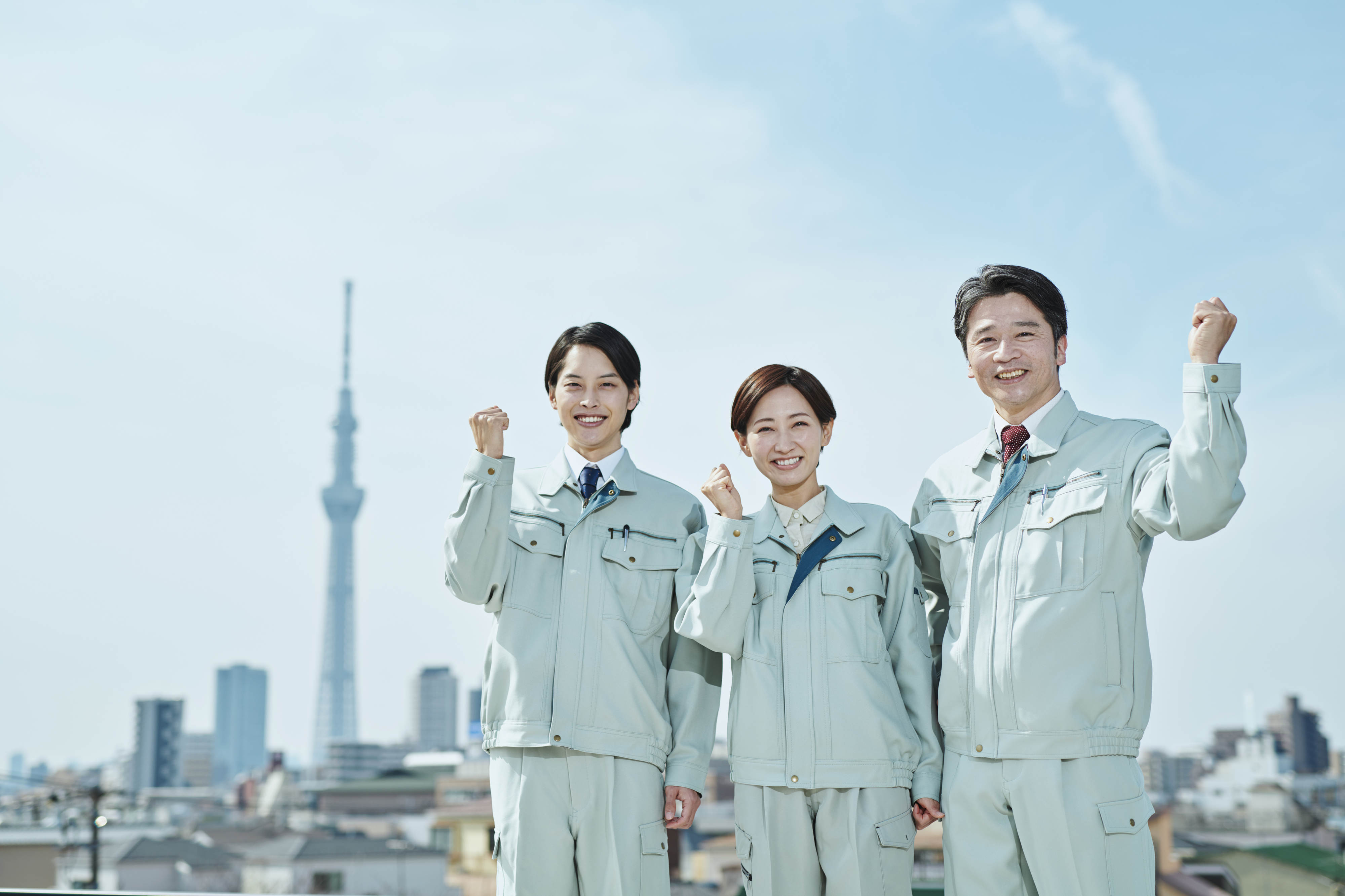 グリーン作業服の建設業者がガッツポーズしています